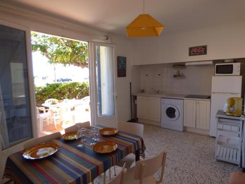 une salle à manger avec une table et une cuisine dans l'établissement Appartement T3, RDC, 4 couchages, Front de Mer Narbonne Plage, à Narbonne-Plage
