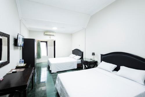 a hotel room with two beds and a desk at Hotel Galuh Anindita in Yogyakarta