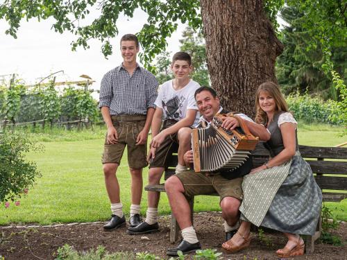 a group of people sitting on a park bench with an accordion at Obst- und Ferienhof Gomeringer in Immenstaad am Bodensee