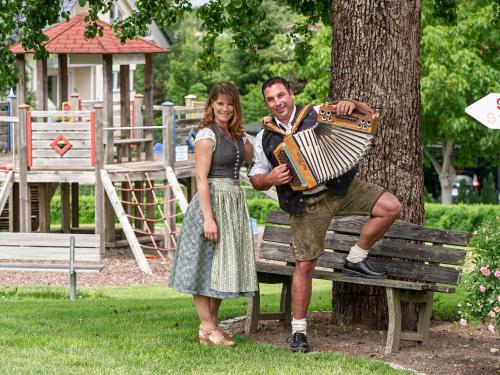 a man and woman standing on a park bench with an accordion at Obst- und Ferienhof Gomeringer in Immenstaad am Bodensee