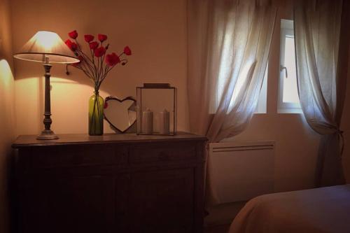 a bedroom with a table with a vase of roses and a lamp at Mas de L Angeos in Velleron