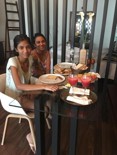 two women sitting at a table with food and drinks at Eden Studio Apartments - 1 in Colombo