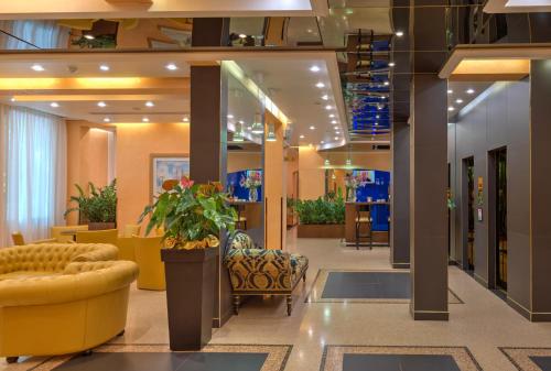 a lobby with a waiting area with a plant and chairs at Central Park Hotel Modena in Modena