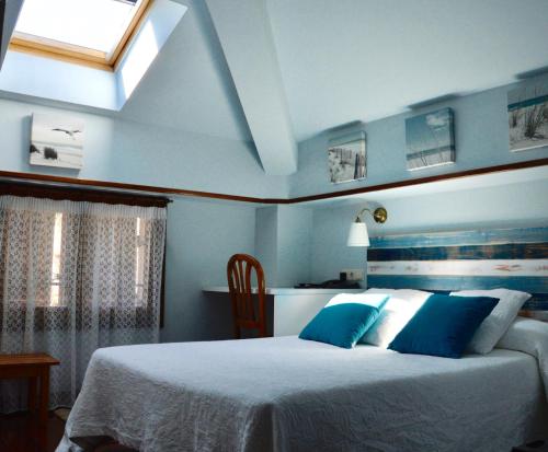 a bedroom with a bed with blue walls and a window at Hotel Alameda in Zarautz