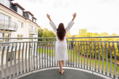a woman standing on a balcony with her arms in the air at Parkhotel Hachenburg in Hachenburg