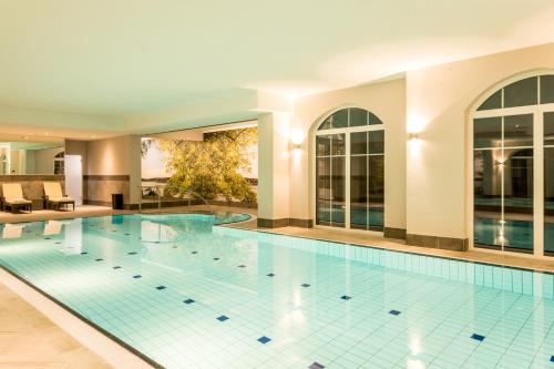 a large swimming pool with blue tiles in a building at Parkhotel Hachenburg in Hachenburg
