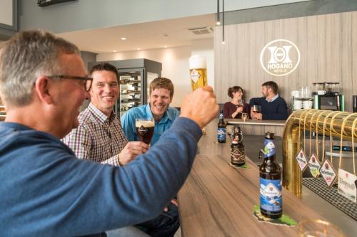 a man holding a glass of wine at a bar at Parkhotel Hachenburg in Hachenburg