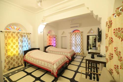 una camera da letto con due letti, un tavolo e finestre di Chanod Haveli a Jodhpur