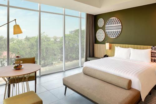 马卡萨Mercure Makassar Nexa Pettarani的带床、桌子和窗户的卧室