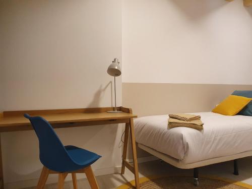 a bedroom with a bed and a desk and a blue chair at Silken Casa Platerias Siglo XV in Zaragoza