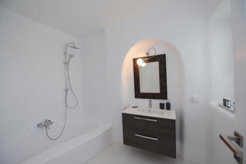 a white bathroom with a sink and a mirror at Diles Villas & Suites Mykonos in Tourlos
