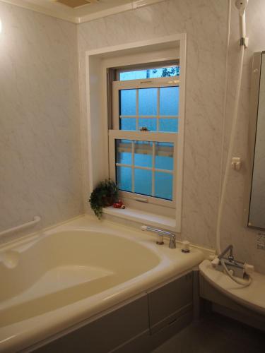 a white bathroom with a tub and a window at Agri In Holiday in Hirosaki
