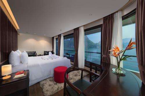 a hotel room with a bed and a desk and window at Scarlet Pearl Cruises - Wonder On Lan Ha Bay in Ha Long