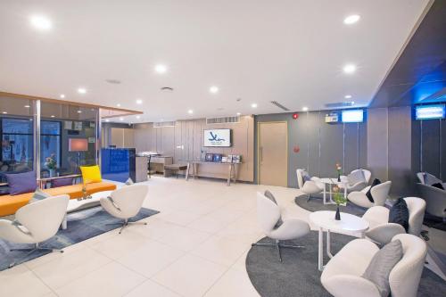 a lobby with white chairs and tables in a building at Xen Hotel Nakhon Pathom - SHA PLUS in Nakhon Pathom