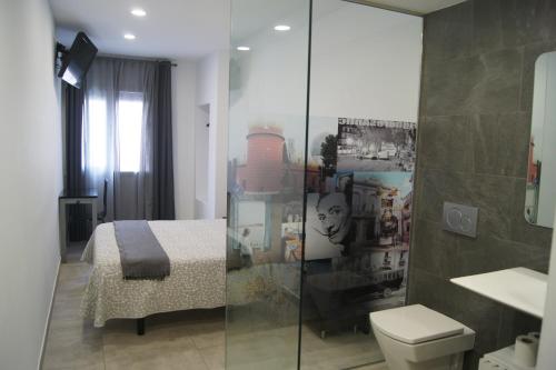 uma casa de banho com uma cama, um WC e um chuveiro em Hostal Sanmar em Figueres