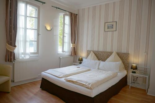 Schlafzimmer mit einem Bett mit weißer Bettwäsche und einem Fenster in der Unterkunft Hotel Am Schloss Biebrich in Wiesbaden
