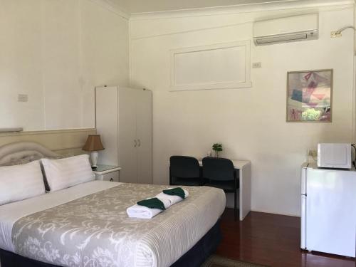 1 dormitorio con cama, escritorio y nevera en Major Innes Motel, en Port Macquarie