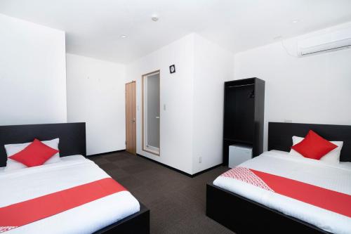 two beds in a room with red pillows at Ｔａｂｉｓｔ ホテル塩釜&松島 in Shiogama