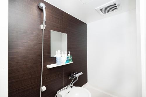 a bathroom with a shower with a toilet and a mirror at Ｔａｂｉｓｔ ホテル塩釜&松島 in Shiogama