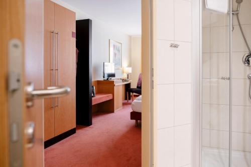 a hotel room with a shower and a bedroom at Hotel am Jungfernstieg in Stralsund