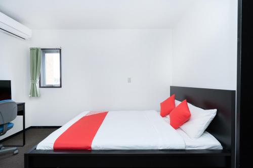a bedroom with a bed with red and white pillows at Ｔａｂｉｓｔ ホテル塩釜&松島 in Shiogama