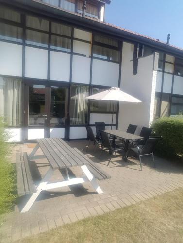 a table and chairs with an umbrella in front of a building at Huisje aan zee in Middelkerke