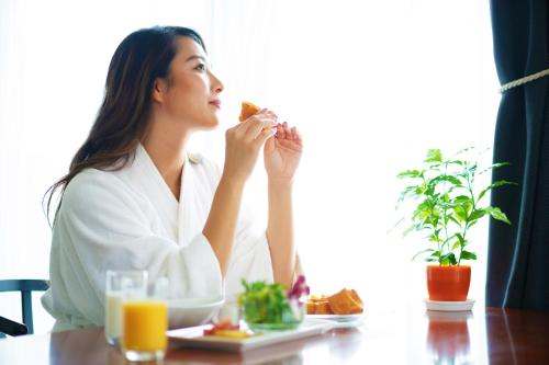 a woman sitting at a table eating a sandwich at Villa Concordia Resort & Spa in Hakodate