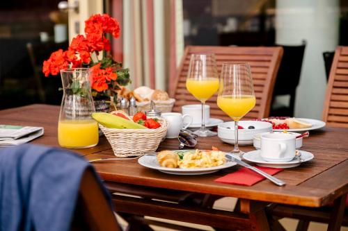 a wooden table with plates of food and glasses of orange juice at Hotel am Jungfernstieg in Stralsund