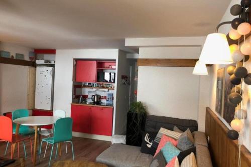 uma sala de estar com uma mesa e uma cozinha com armários vermelhos em Modern Apartment In La Plagne 1800 em Mâcot La Plagne