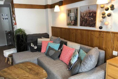 uma sala de estar com um sofá cinzento com almofadas coloridas em Modern Apartment In La Plagne 1800 em Mâcot La Plagne