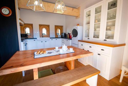 a kitchen with white cabinets and a wooden table at Villa z widokiem na Giewont in Kościelisko