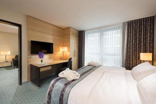 a hotel room with a bed and a desk and a television at Maritim Hotel Düsseldorf in Düsseldorf