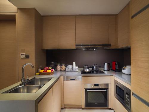 a kitchen with wooden cabinets and a sink at Fraser Suites Guangzhou in Guangzhou