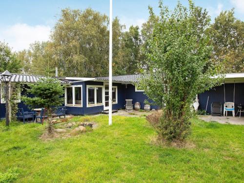 a blue house with a tree in the yard at 8 person holiday home in Dannemare-By Traum in Dannemare