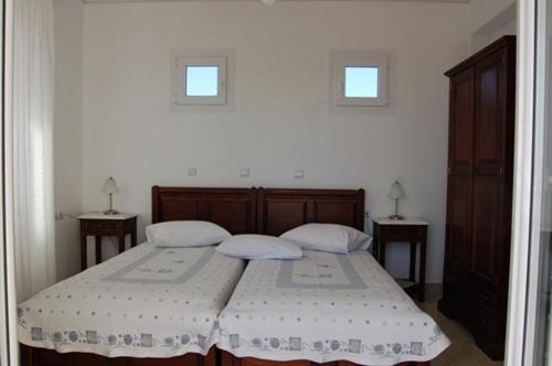 two beds in a room with two tables and two windows at Villa Vourda in Marathokampos