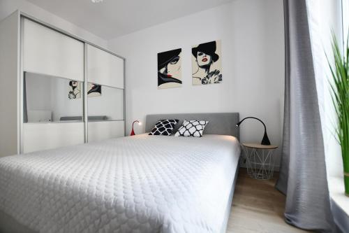 a bedroom with a white bed and two pictures on the wall at Apartament El Rojo z garażem in Kołobrzeg
