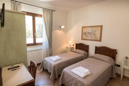 アッシジにあるBed & Breakfast Al Pian d'Assisiのベッド2台、テーブル、窓が備わる客室です。