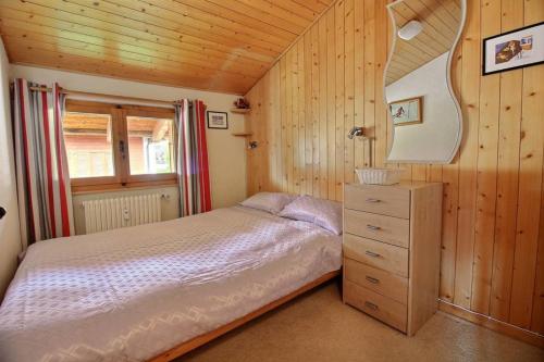 1 dormitorio con 1 cama y pared de madera en Clair Abri 104, en Verbier