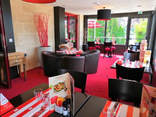 サン・テミリオンにあるイビス ボルドー サン テミリオンの赤い絨毯が敷かれたレストランで、黒いテーブルと椅子が備わります。