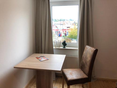 a wooden table and a chair in front of a window at Ferienwohnung 3 zwischen Nürnberg und Regensburg in Deining
