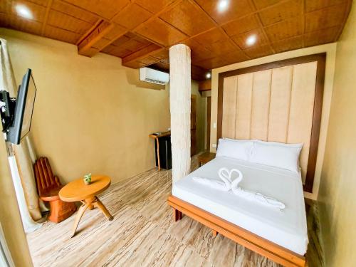 a bedroom with a white bed with a wooden floor at Kaiyana Boracay Beach Resort in Boracay