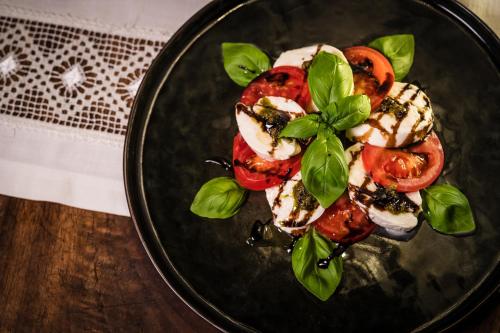a black plate of food with tomatoes and basil at Das Halali - dein kleines Hotel an der Zugspitze in Ehrwald