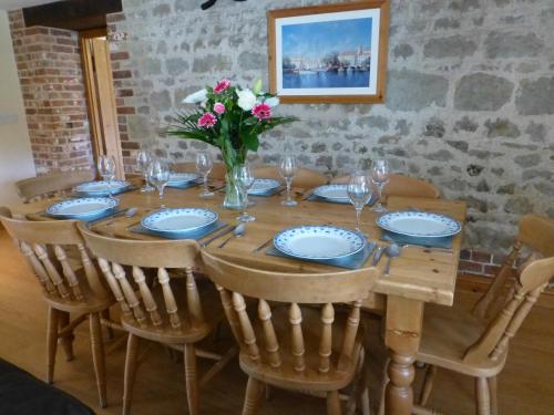 uma mesa de madeira com cadeiras e um vaso de flores em Great Coombe, Bookham Court em Dorchester