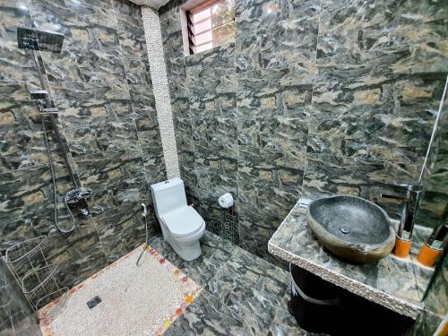 a stone bathroom with a toilet and a sink at Kaiyana Boracay Beach Resort in Boracay