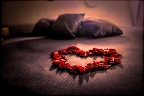 un cœur en pétales de rose rouge sur un lit dans l'établissement LOVE Suites & SPA "Le Chai" avec lit rond, à Médis