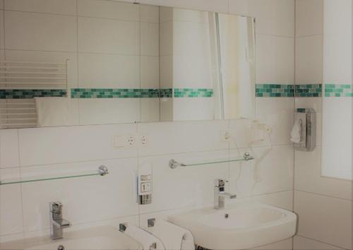 a white bathroom with a sink and a mirror at Hotel Germersheimer Hof in Germersheim