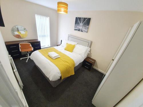 a bedroom with a large bed with a yellow blanket at Salford Holiday Apartment Manchester in Manchester