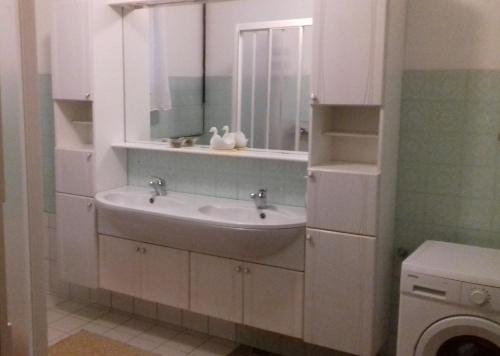 a white bathroom with a sink and a mirror at Apartma Kolpa in Gradac