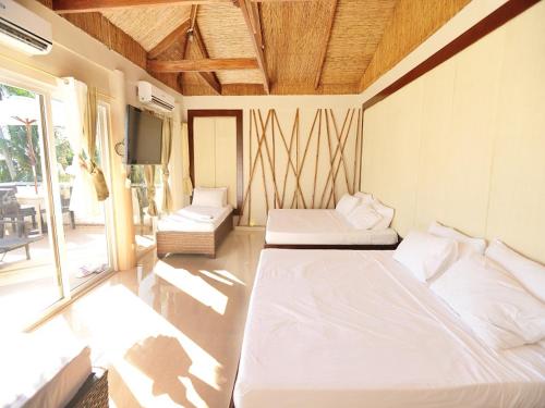 a bedroom with two beds and a television in it at Kaiyana Boracay Beach Resort in Boracay