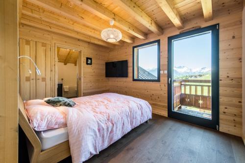 a bedroom with a bed and a large window at Harfang des Neiges in La Toussuire